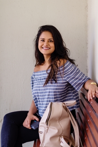 young indian woman at bus stop - Australian Stock Image