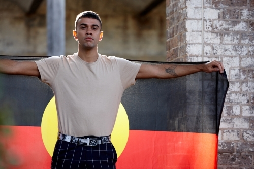Young Indigenous Australian man holding Aboriginal flag - Australian Stock Image