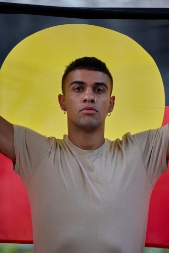 Young Indigenous Australian man holding Aboriginal flag - Australian Stock Image
