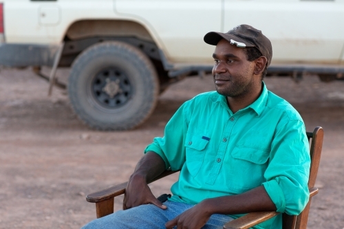 Young indigenous man relaxing in chair outdoors - Australian Stock Image