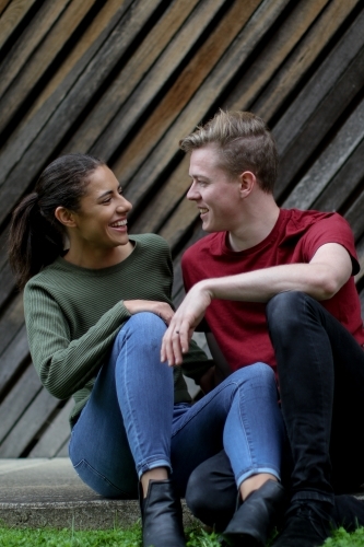 Young interracial couple laughing together in front of textured wooden panels