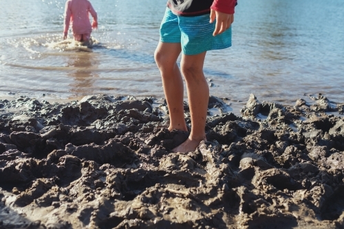 young kids playing in the muddy beach - Australian Stock Image