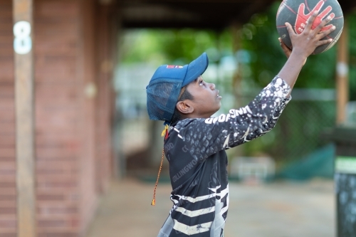 young lad shooting basketball outside his home - Australian Stock Image