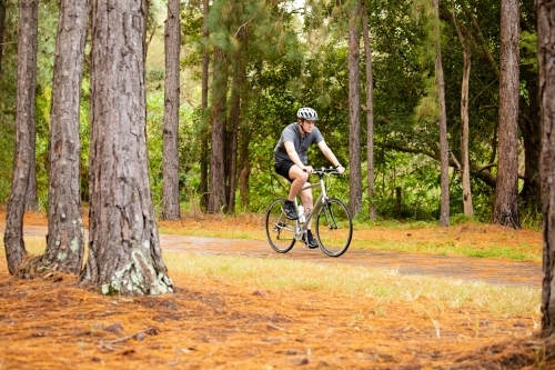 Young male cycling along a parkland bike path - Australian Stock Image