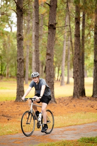 Young male cycling along a parkland bike path - Australian Stock Image