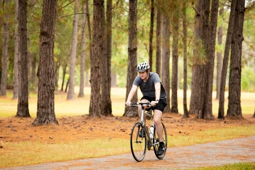 Young male cycling along a parkland bike path - Australian Stock Image