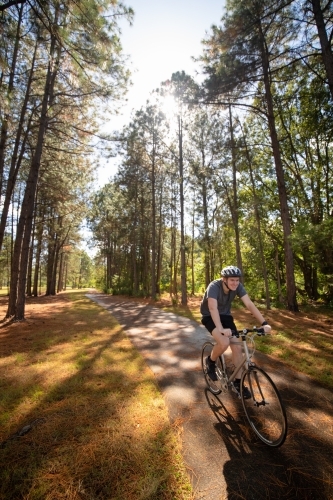 Young male cycling along a parkland bike path - Australian Stock Image