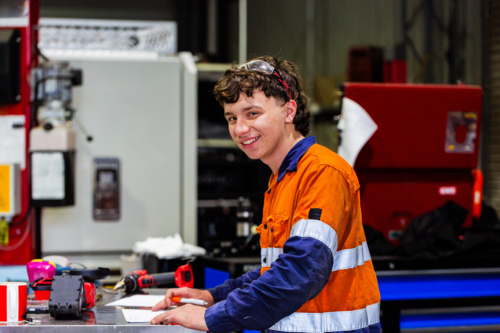 Young male mechanic working at tool bench doing paperwork on vehicle fitout - Australian Stock Image