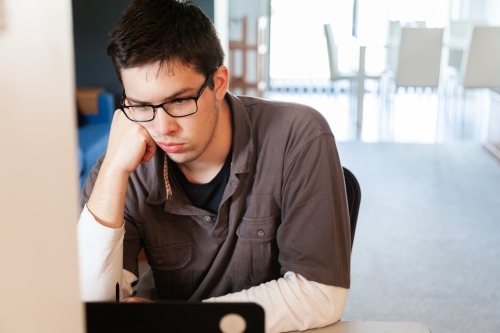 Young male uni student studying math on laptop for exams from home during covid-19 - Australian Stock Image