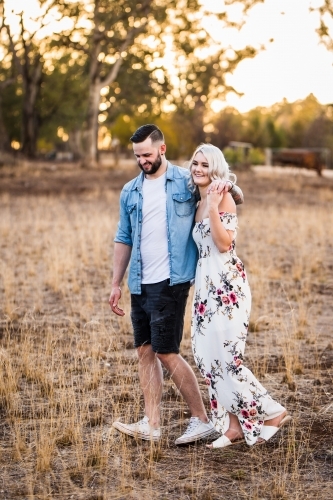 Young man and woman walking with arms around each other - Australian Stock Image