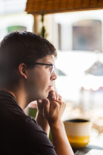 Young man at a cafe looking out the window - Australian Stock Image
