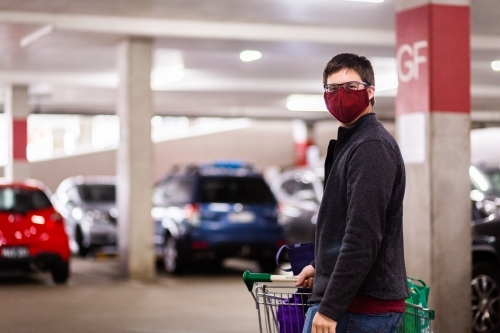 Young man doing the shopping and taking re-usable bags of groceries to the car