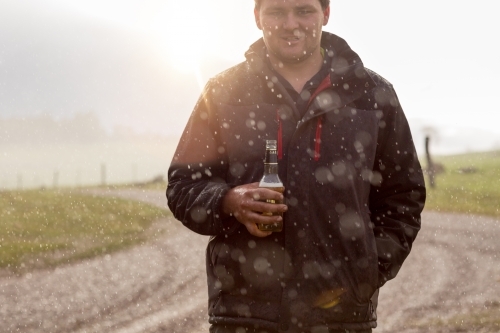 Young man having a beer in the rain - Australian Stock Image