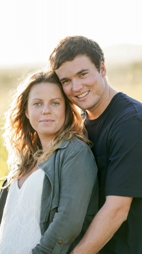 Young man hugging pregnant wife from behind - Australian Stock Image