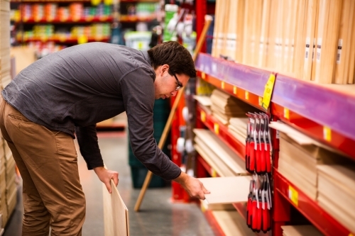 Young man in wood section of hardware store - Australian Stock Image