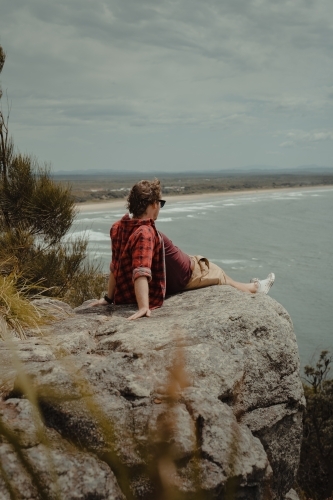 Young man relaxing at a lookout overlooking the beach and ocean at Evans Head. - Australian Stock Image