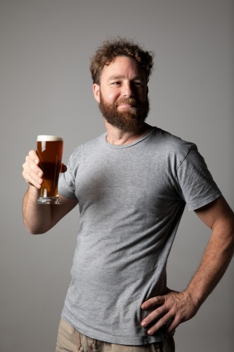 Young man sitting, holding a glass of beer, relaxed and happy