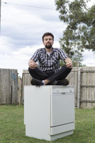 Young Man sitting on Dishwasher - Australian Stock Image