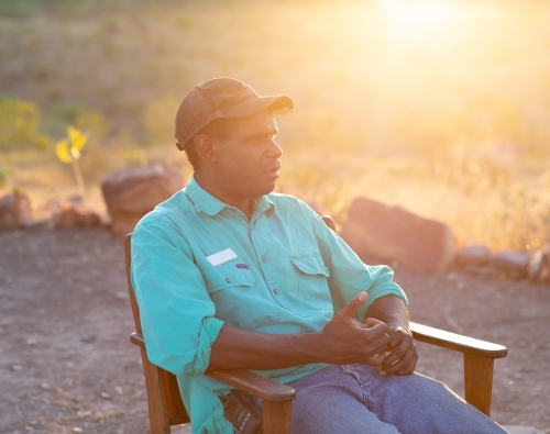 Young man sitting outdoors with sun flare - Australian Stock Image