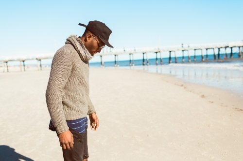 Young man standing on the beach looking down - Australian Stock Image