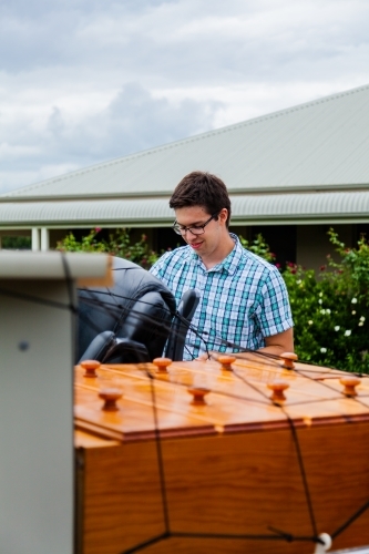 Young man tying down netting on ute trailer with furniture packed for moving - Australian Stock Image