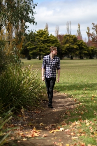 Young man walking alone along a path in nature - Australian Stock Image