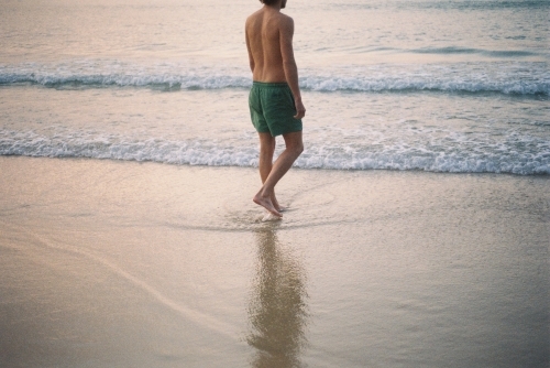 Young man walking towards the ocean