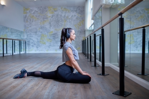 Young Maori girl doing yoga stretch in dance studio - Australian Stock Image