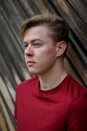 Young melancholy caucasian man modelling in front of a wooden panelled background