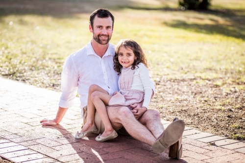 Young mixed race Aboriginal girl sitting on Caucasian father's lap