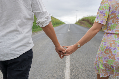 Young mixed race couple holding hands on the road - Australian Stock Image