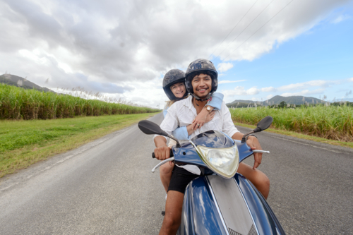 Young mixed race couple riding a motorbike together on a Queensland country road - Australian Stock Image