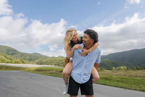 Young mixed race couple smiling and in love during a piggyback ride - Australian Stock Image