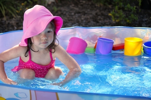 Young mixed race girl playing in a small pool in Australian backyard - Australian Stock Image