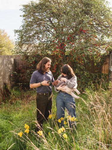 Young mother breastfeeding baby in an overgrown garden - Australian Stock Image