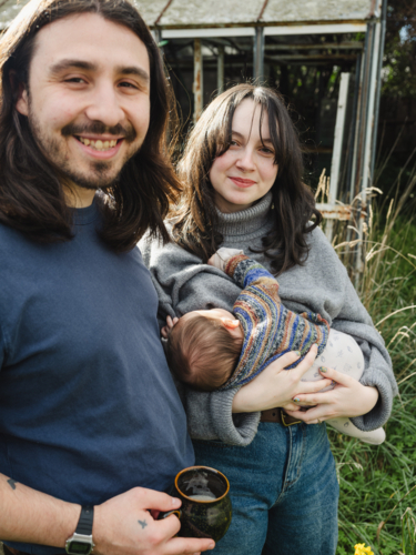 Young mother breastfeeding baby in an overgrown garden - Australian Stock Image