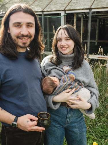 Young mother breastfeeding baby in an overgrown garden - Australian Stock Image