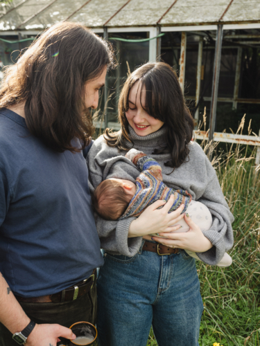 Young mother breastfeeding baby in an overgrown garden - Australian Stock Image