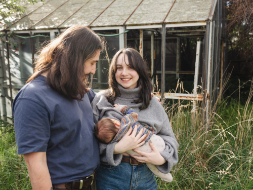 Young mother breastfeeding baby in an overgrown garden - Australian Stock Image