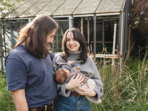 Young mother breastfeeding baby in an overgrown garden - Australian Stock Image