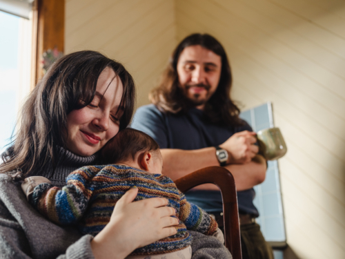 Young mother holding baby dressed in striped sweater - Australian Stock Image