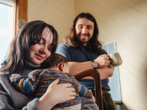 Young mother holding baby dressed in striped sweater - Australian Stock Image