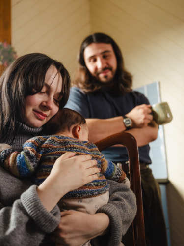 Young mother holding baby dressed in striped sweater - Australian Stock Image