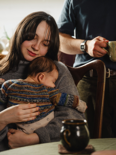 Young mother holding baby dressed in striped sweater - Australian Stock Image