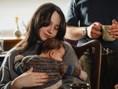 Young mother holding baby dressed in striped sweater - Australian Stock Image