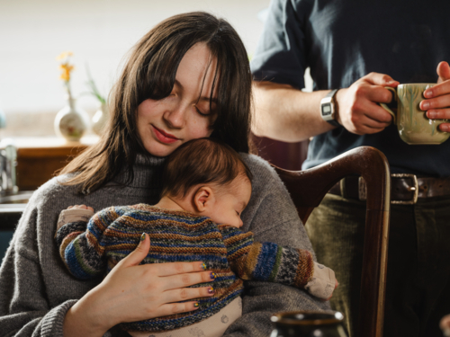 Young mother holding baby dressed in striped sweater - Australian Stock Image
