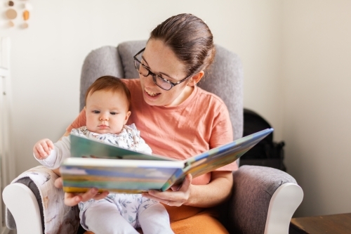 Young mother together with baby reading a picture book
