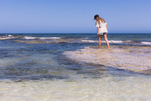 Young Person Standing in Shallow Water at Australian Beach - Australian Stock Image
