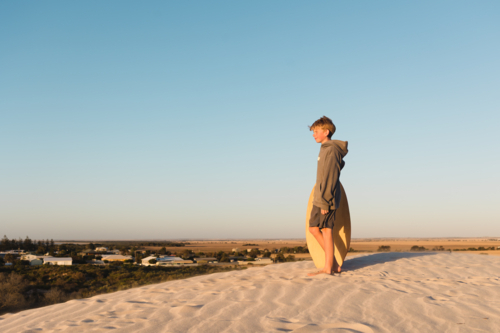 Young Person Standing on a White Sand Dune Overlooking the Australian Outback Landscape - Australian Stock Image