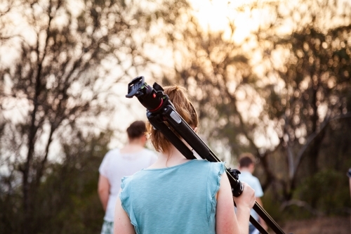 Young photographer carrying tripod to location for family photos - Australian Stock Image
